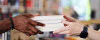 A set of hands pass a stack of books from left to right