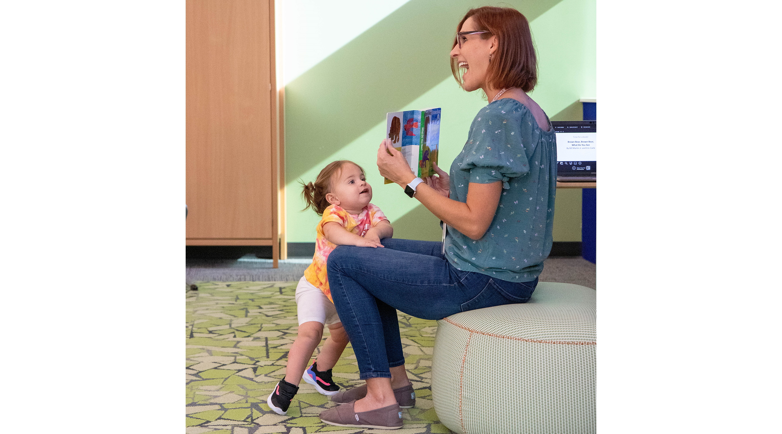 a toddler enjoys storytime with an adult holding a book