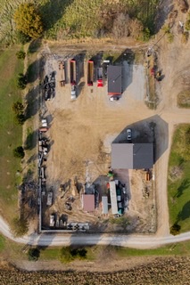 Aerial view of rural dirt lot with trucks and two small buildings.