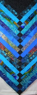 Textile panel with strips of blue hued fabric creating a chevron pattern.