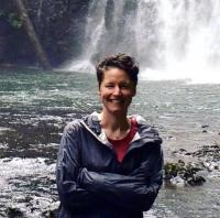 Smiling woman standing in front of a waterfall.