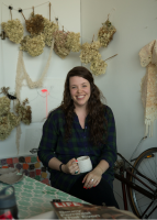 woman sitting beside a table with with art in the background