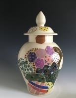 Stoneware jar covered in glazed, colorful quilt patterns.