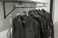 Detail photo of art installation: black shirts hanging on a clothing rod