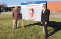 Two men stand next to a sign in Merriam, Kansas that says "Future site of Johnson County Library"