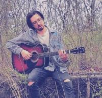 man with guitar in a field