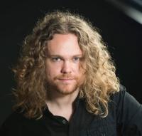 male with long curly hair smiling