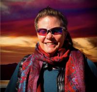 Photograph of artist Jennifer Walker in front of a sunset.