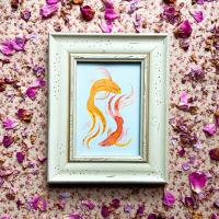Framed watercolor painting of two gold fish, set on top of floral fabric and decorated with pink flower petals.