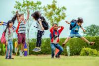 5 young children wearing backpacks playing in a park