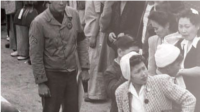 A black and white photo of people standing in line