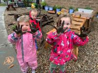 Children holding up muddy fingers. 