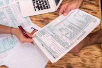 Tax forms being handed across a table.