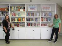 Two librarians pose with books arranged on bookshelves