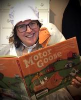 Miss Becky holds a picture book called Motor Goose while a plush goose reads over her shoulder