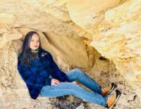 Woman wearing hiking gear reclines among a rock formation