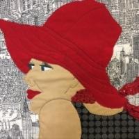 Quilted portrait of a woman in a red hat.