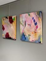 Two, multi colored abstract paintings hanging on a wall.