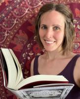 Sasha Smith holding a book in front of a red patterned background