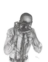 A black man holding a camera and peering through the lens taking our photo.