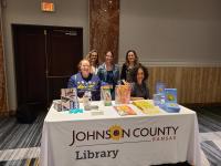 librarians pose behind a conference table with library flyers on top