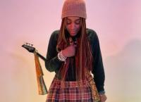 Black female in knit cap, long skirt and guitar