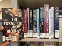 The Forgetting by Hannah Beckerman being pulled off a shelf of other books