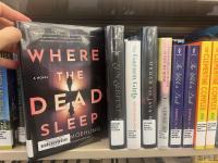 The book Where the Dead Sleep being pulled of a book shelf