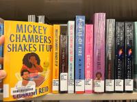 The book Mickey Chambers Shakes It Up being pulled from a bookshelf of other books with library labels on their spines