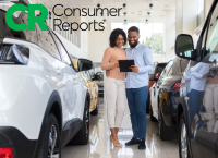 a man and a woman look at a tablet in a car dealership