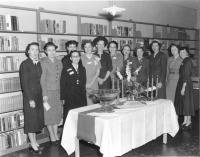The Founding Mothers of Johnson County Library group photo in front of book shelving at an open house for the Library's temporary headquarters. 