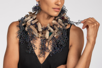 Photo of a woman wearing a sculptural necklace made from mixed materials.