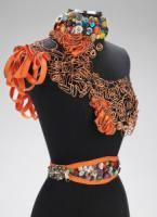 Photo of a dress form wearing sculptural jewelry made from mixed materials.
