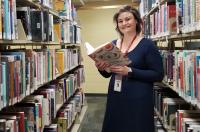 Diana Spencer in a library aisle with a cookbook in her hands