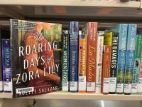 The book The Roaring Days of Zora Lily being pulled off of a shelf of other library books