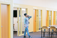 Photograph of a student leaving a study room among a row of study rooms.