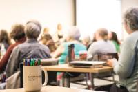 A mug that reads "Johnson County Library" sits on a table. People are sitting in the background at other tables.