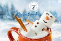 A marshmallow snowman uses a mug of hot cocoa as a hot tub in a snowy winter scene.