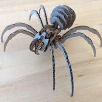 laser cut spider unpainted Table with wooden tabletop. On the table, an unpainted laser cut cardboard spider, assembled.