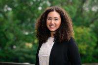 Theresa Kopper Young smiling woman with long curly hair parted in middle in a white shirt and dark jacket