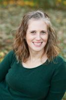 Woman in green sweater smiling looking into camera