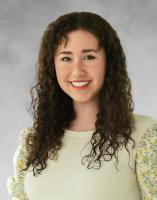 Theresa Kopper smiling person with long wavy dark hair in a light green sweater