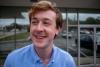 red-haired, smiling young man in a blue collared shirt