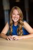 smiling woman with long strawberry blond hair in a blue sleevless top