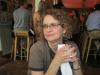 Curly-haired blond woman with glasses, hands folded in front of her, looking pensive