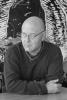 Steve Brisendine bald man with glasses in long sleeved shirt looking pensive
