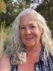 white woman with long grey hair in a blue plaid sleeveless shirt