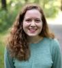 Lindsey Weishar smiling woman with long red curly hair and a bluish green sweater