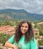 woman in green short sleevs dark curly hair with mountains in the background Theresa Kopper