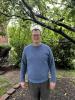 Jared Campbell man standing outside in a light blue sweater, glasses, grey pants